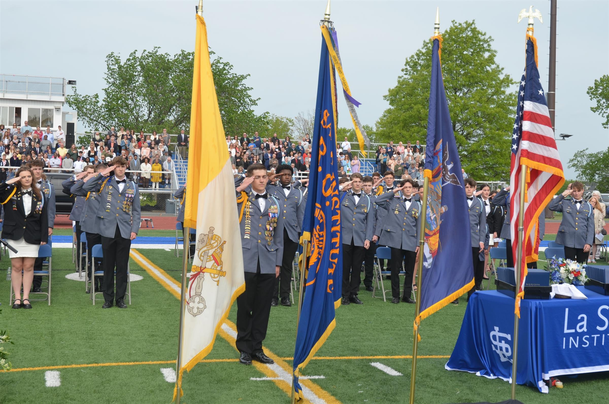 students saluting at graduation